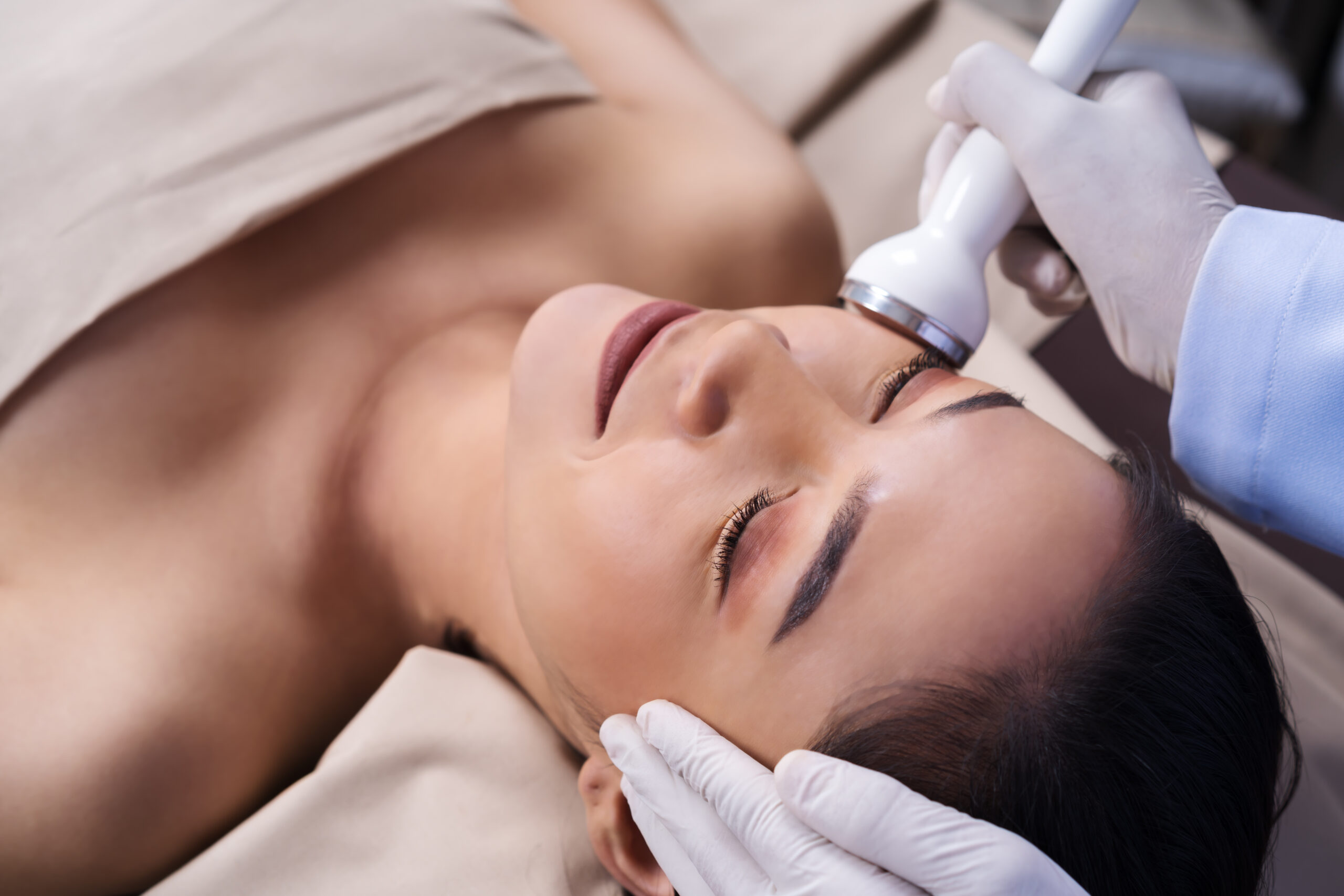 young woman receiving ultrasound facial beauty treatment skin care